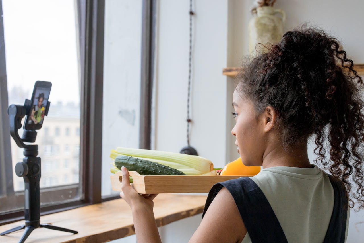 A young woman vlogging her healthy cooking session using a smartphone indoors.